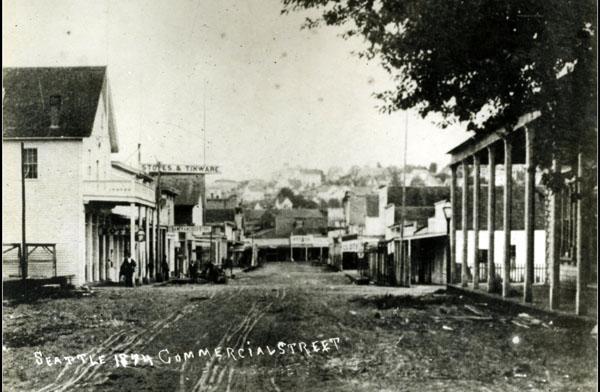 State Library Photograph CollectionAR-07809001-ph002110Photo shows unpaved street and store buildings with signs including Stoves and Tinware