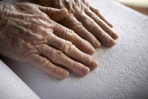 Photo of older person reading braille text